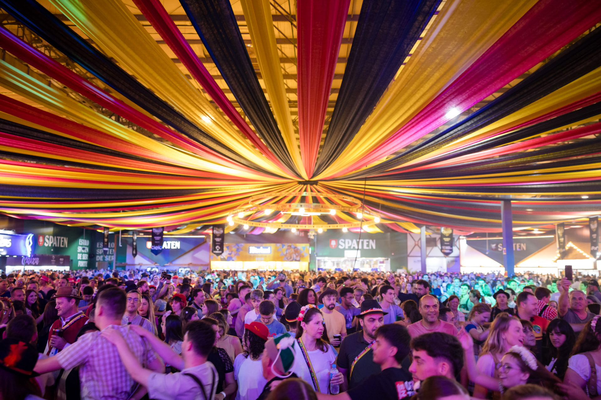 Tenda com decoração colorida e público em festa
