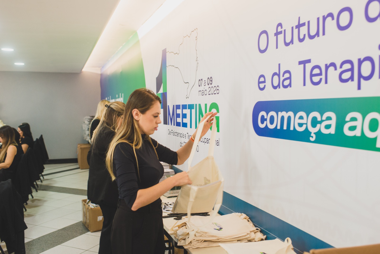 Recepcionista organizando materiais no balcão de credenciamento